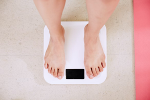 A person stands on a weighing scale to check their weight.